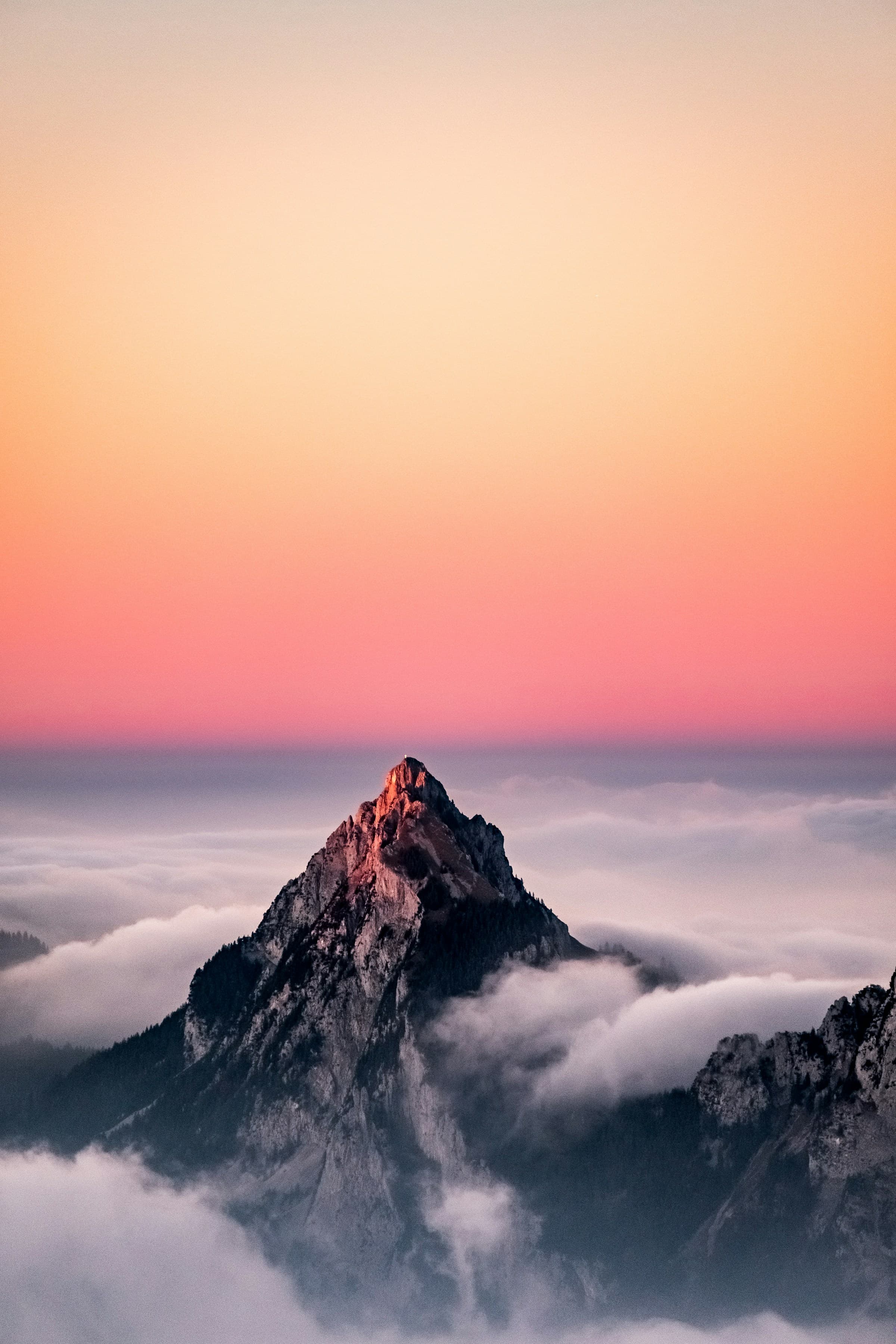 A mountain summit breaking through a sea of cloud at dawn
